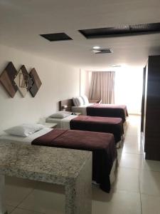 um quarto de hotel com três camas e um sofá em FLAT 134 - Imperial Flat Tambaú Nobile, beira-mar em João Pessoa em João Pessoa