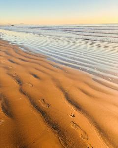 una spiaggia con impronte di piedi nella sabbia e nell'oceano di Sumner Bay Motel a Christchurch