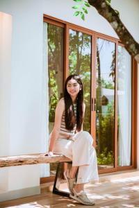 a woman sitting on a bench in front of a window at Nainan resotel ในน่าน รีโซเทล in Nan