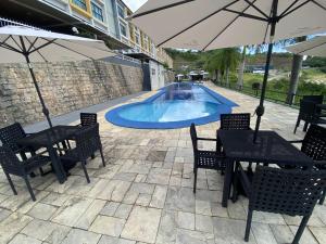 a pool with tables and chairs and an umbrella at Apt Alto da Serra Villas - Bananeiras in Bananeiras