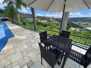 a table and chairs with an umbrella next to a swimming pool at Apt Alto da Serra Villas - Bananeiras in Bananeiras