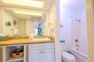 a bathroom with a sink and a toilet and a mirror at Seagulls Serenade Cozy 1BR Hideaway near Beach 206 in South Padre Island +18 photos
