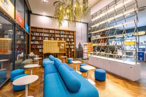a library with blue chairs and tables and bookshelves at JK Blossom Hotel in Seoul