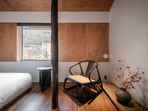a bedroom with a chair and a bed and a window at Kotohi Machiya House in Kyoto
