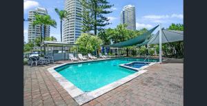 uma piscina com tenda, cadeiras e edifícios em Bayview Bay Apartment and Marina em Gold Coast