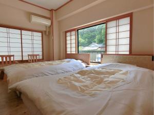 two beds in a room with large windows at Minshuku Inn Shirahama Ekinoyado in Shirahama