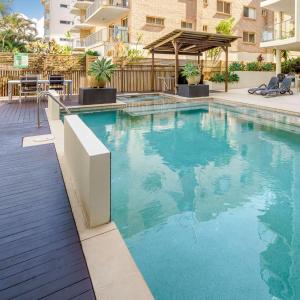 a swimming pool with blue water in a building at Hamptons Style Penthouse at Kings Beach in Caloundra