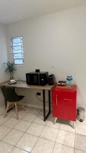 a desk with a microwave and a red refrigerator at Conforto e localização - São Paulo Expo in Sao Paulo