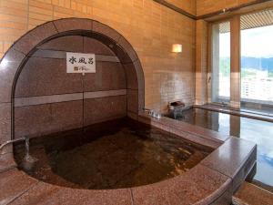 a large pool of water in a building with a sign at KKR Yuzawa Yukiguni in Yuzawa