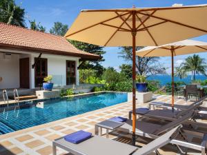 a pool with chairs and umbrellas next to a house at Infinity View by Elite Havens in Kata Beach