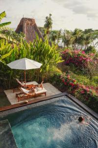 a pool with two people laying in a chair and an umbrella at NIHI Sumba in Watukarere