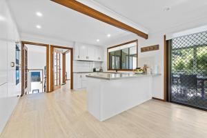 Una cocina con gabinetes blancos y encimera. en Fuller Holidays - Maluco - Beach House Belongil, en Byron Bay