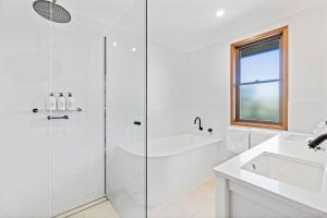 Un baño blanco con ducha y lavabo. en Fuller Holidays - Maluco - Beach House Belongil, en Byron Bay 8 fotos más