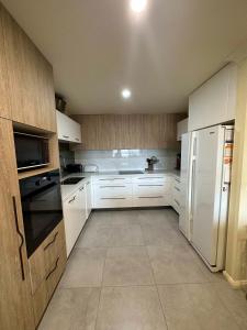 Una cocina con gabinetes blancos y un refrigerador blanco. en Apartment in the Heart of Bathurst Walk Everywhere, en Bathurst