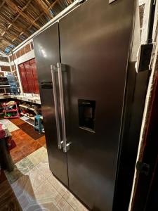 a stainless steel refrigerator in a kitchen with a garage at Sea la vie casita in Las Peñitas