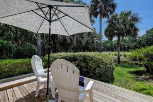 two white chairs and an umbrella on a wooden deck at Evian 156 in Hilton Head Island