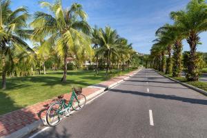 a bike parked on the side of a road with palm trees at Laguna Park Townhomes & Villas in Bang Tao Beach
