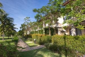 a building with trees and bushes next to a sidewalk at Laguna Park Townhomes & Villas in Bang Tao Beach