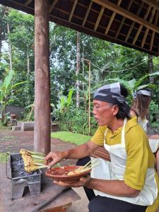 a man holding a plate of pizza on a grill at Pondok Masa Depan in Sidemen
