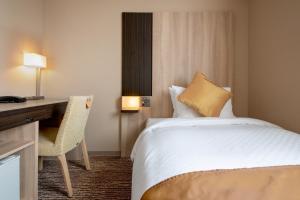 仙台市にあるホテルビスタ仙台のベッドとデスクが備わるホテルルームです。