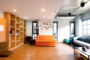 a living room with an orange ottoman and a couch at Travelier Hostel in Bangkok