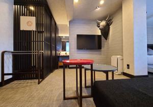 Cette chambre d'hôtel dispose d'une table rouge et d'une télévision. dans l'établissement Koyado Enn, à Toyooka