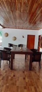 a dining room table with chairs and a wooden ceiling at Rumah Pantai Patang in Jati