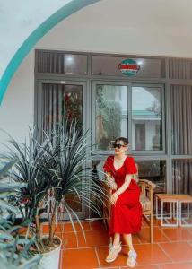 Una mujer con un vestido rojo sentada en un porche en Tropical Homestay Phu Yen en Tuy Hoa