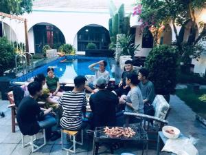 een groep mensen die rond een tafel bij een zwembad zitten bij Tropical Homestay Phu Yen in Tuy Hoa