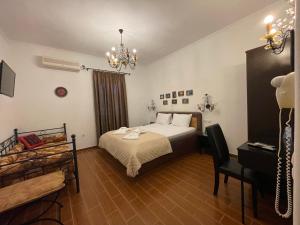 a bedroom with a bed and a desk and a chandelier at Alice Maisonette & Studios in Adamas