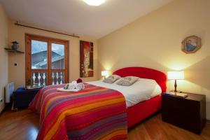ein Schlafzimmer mit einem roten Bett mit einer bunten Decke in der Unterkunft Appartement Beauregard 1 - Happy Rentals in Les Houches