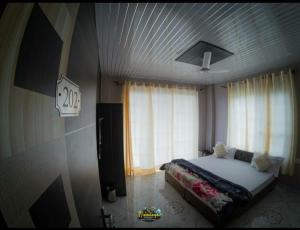 ein Schlafzimmer mit einem Bett und einem großen Fenster in der Unterkunft Himalayan Musaafir Guest House & Restaurant in Dharamshala