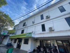 un bâtiment blanc avec une pancarte sur le côté dans l'établissement RedDoorz at Jalan Sam Ratulangi Manado, à Manado