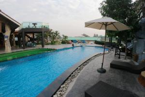 Chai Nat的住宿－Suwanna Riverside，一座带遮阳伞的游泳池位于大楼旁