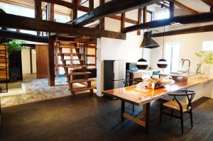 a large kitchen with a wooden table and a dining room at 寝室から一望できる阿蘇山の絶景!!築200年の歴史ある米蔵をリノベーションした一棟貸しの宿 in Bōchū