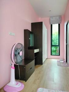 um quarto rosa com um quarto rosa com uma ventoinha em Hana Villa Hatyai em Suen Phra