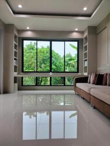 a living room with a couch and a large window at Hana Villa Hatyai in Suen Phra