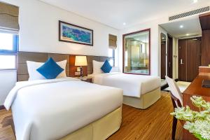ダナンにあるPavilion Hotel Da Nangのベッド2台とデスクが備わるホテルルームです。
