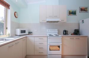 eine weiße Küche mit einem Herd und einer Mikrowelle in der Unterkunft Silver Birches Holiday Village - Unit 3 in Bright