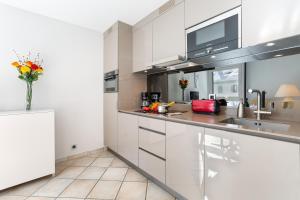 Appartement L'Outa 209 - Happy Rentals في شامونيه مون بلان: مطبخ مع خزائن بيضاء و إناء من الزهور