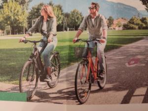 un hombre y una mujer montando bicicletas por una calle en Appartamenti Residenza Dossalt, en Baselga di Pinè