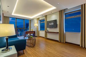 Pavilion Hotel Da Nang في دا نانغ: غرفة في الفندق مع أريكة زرقاء وتلفزيون