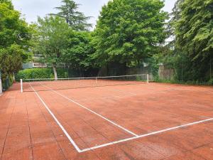 a tennis court with a net on it at EXIGEHOME-Maison avec piscine et tennis à 30 min de Paris in Saint-Gratien