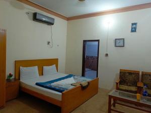 um quarto com uma cama, uma cadeira e uma janela em SEE MOTEL em Muzaffarabad