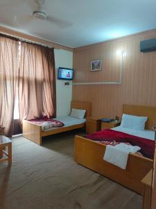 Habitación de hotel con 2 camas y TV en SEE MOTEL en Muzaffarabad