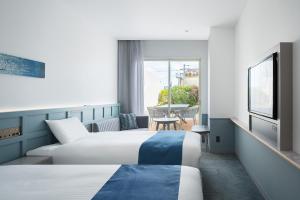 Habitación de hotel con 2 camas y balcón en Lequ Okinawa Chatan Spa ＆ Resort, en Chatan