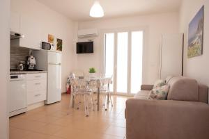 a kitchen and a living room with a couch and a table at Appartamento Conturrana Sul Mare in San Vito lo Capo