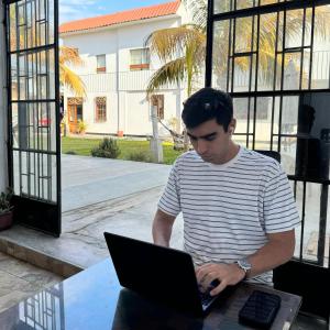 パカズマヨにあるLa Arteza Pacasmayoのノートパソコンを使って座っている男