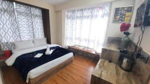 ein Schlafzimmer mit einem großen Bett und einem Fenster in der Unterkunft GRG Olive Branch Darjeeling - Excellent Customer Service in Darjeeling