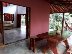 a room with a wooden table and a red wall at Casa Rosa Chá em Lençóis in Lençóis